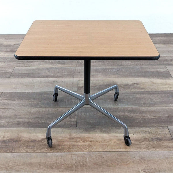 Herman Miller side table with a wooden top and metal legs on wheels.