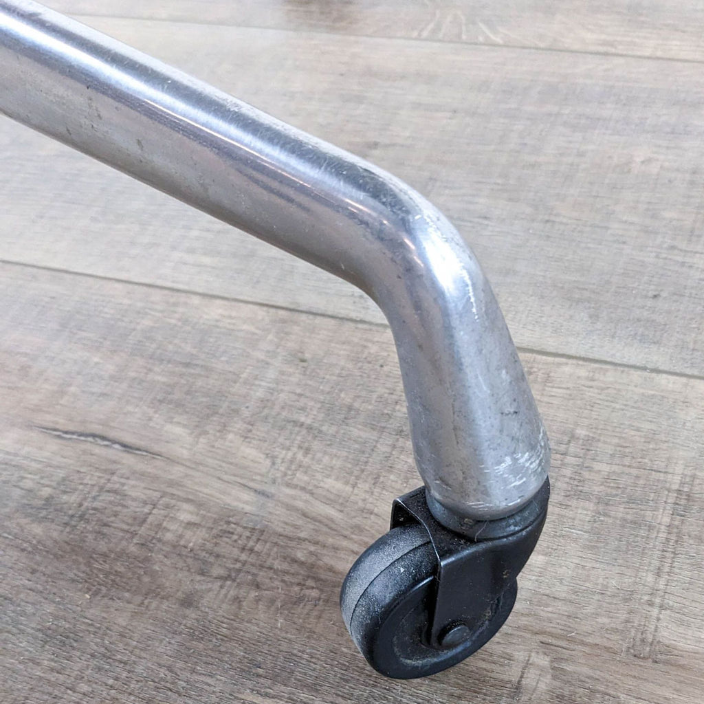 Close-up of the metal leg and caster wheel of the Herman Miller table.