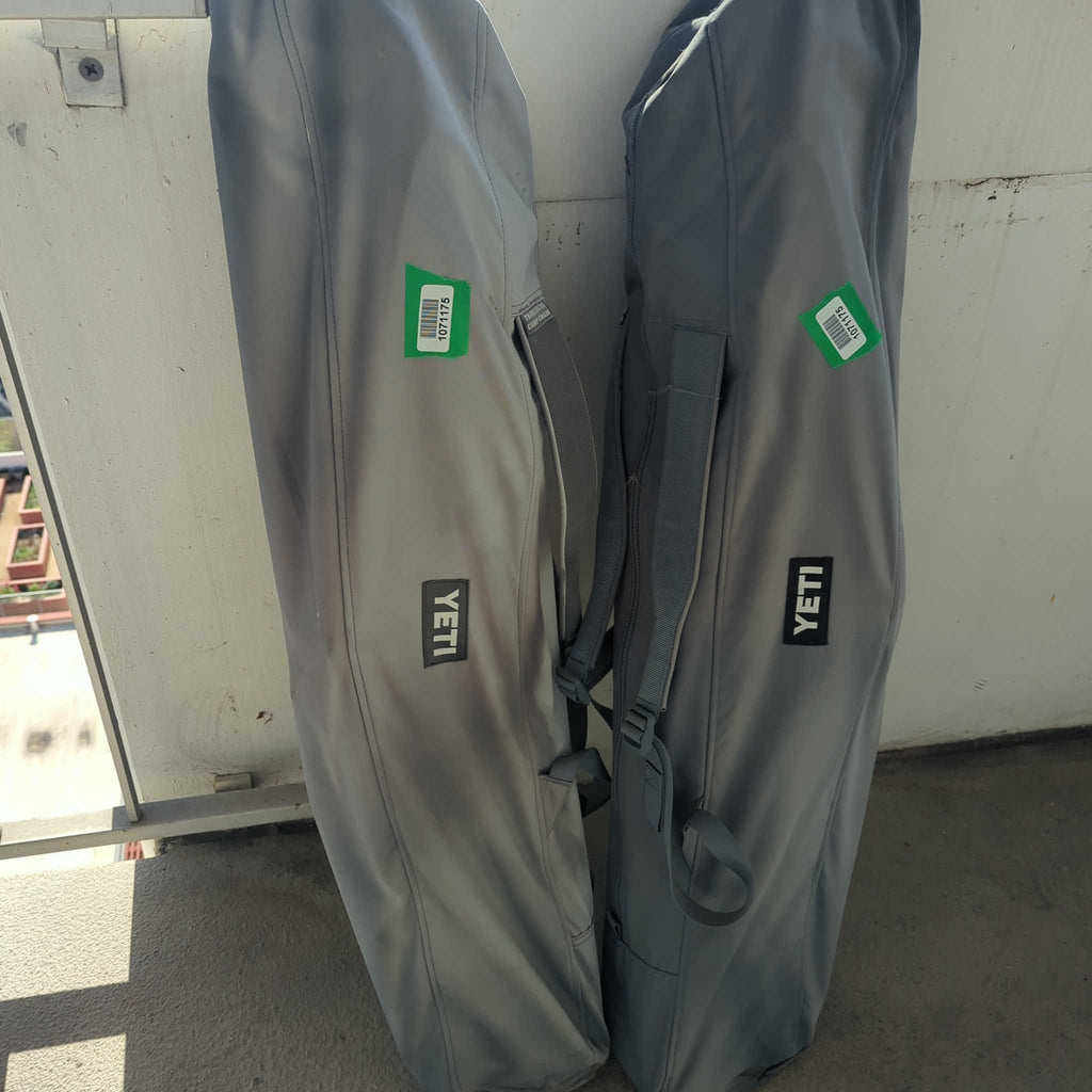 Two Yeti branded chair bags with green labels, placed standing side by side on a balcony floor.