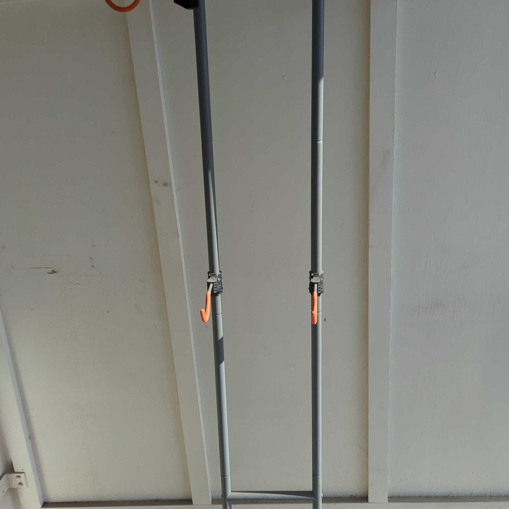 Gray metal outdoor stand with two orange hooks, designed for holding equipment or gear upright.