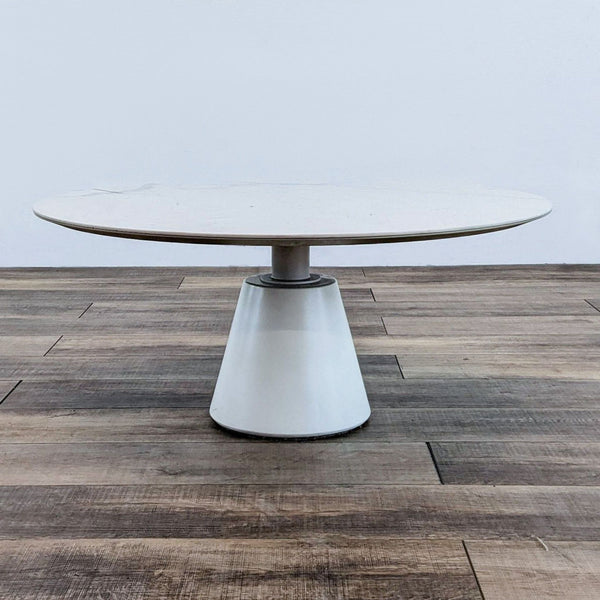 Round coffee table with a powder-coated steel base on wooden floor.