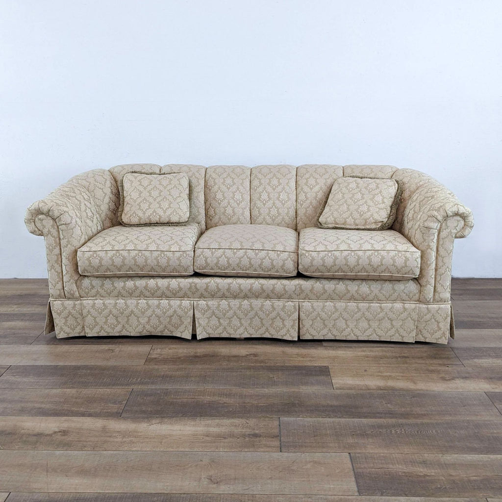 Vintage curved back sofa with damask pattern and pleated skirt, featuring rolled arms.