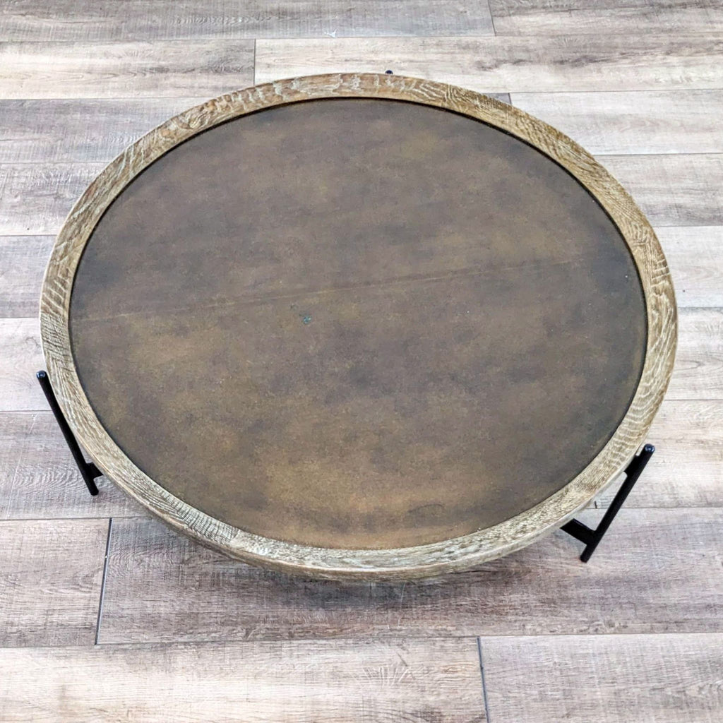 Top view of a round coffee table showing brass-clad surface with oak finish trim.