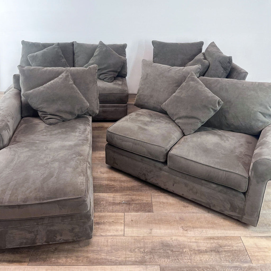 3-seat sectional with chaise, in gray, rounded arms, and plush pillows on a wooden floor.
