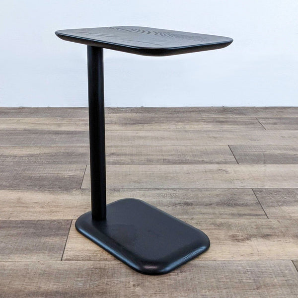 Black side table with a single central leg and rectangular top.  