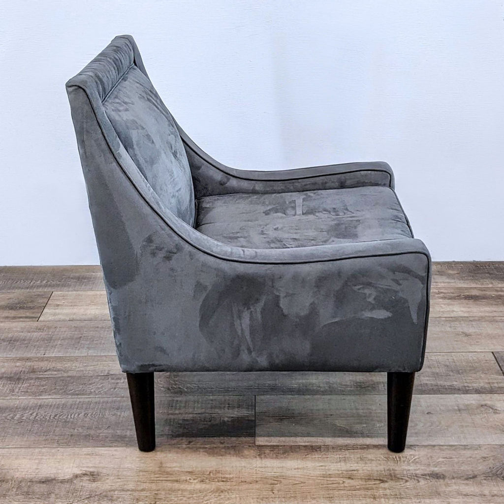 Side view of a gray chair showing sloped narrow arms and plush seating.