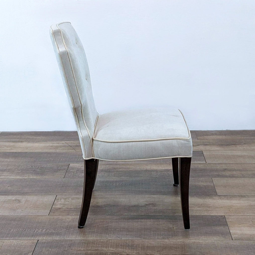Side view of a single Oliixx dining chair, highlighting the button tufted back.  