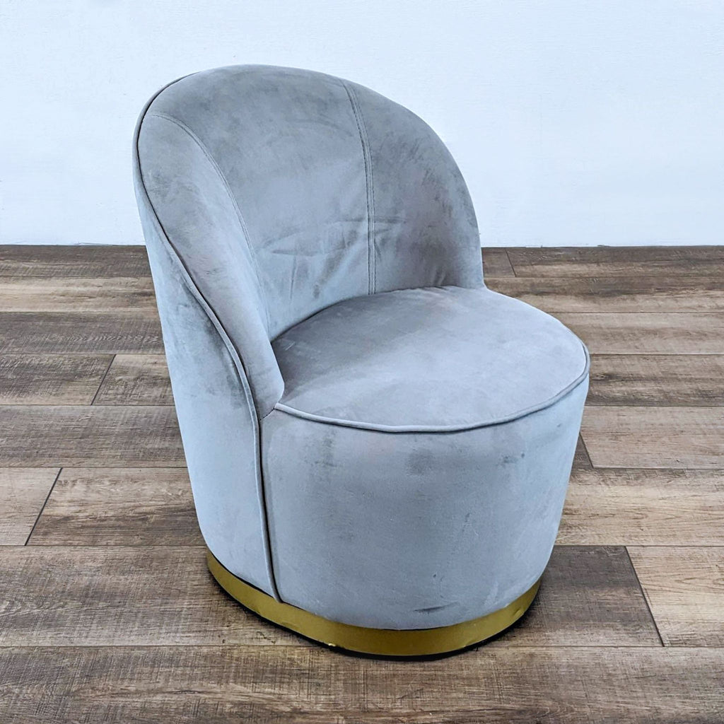 Modern gray velvet chair with a recessed gold base on wood.