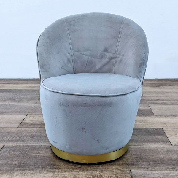 Gray velvet barrel chair with gold base on wooden floor.