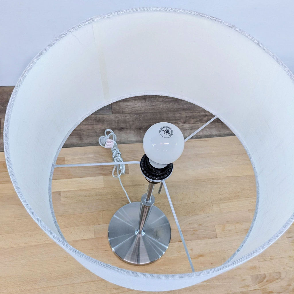 View from above showing the interior of the lamp's white drum shade and steel base.