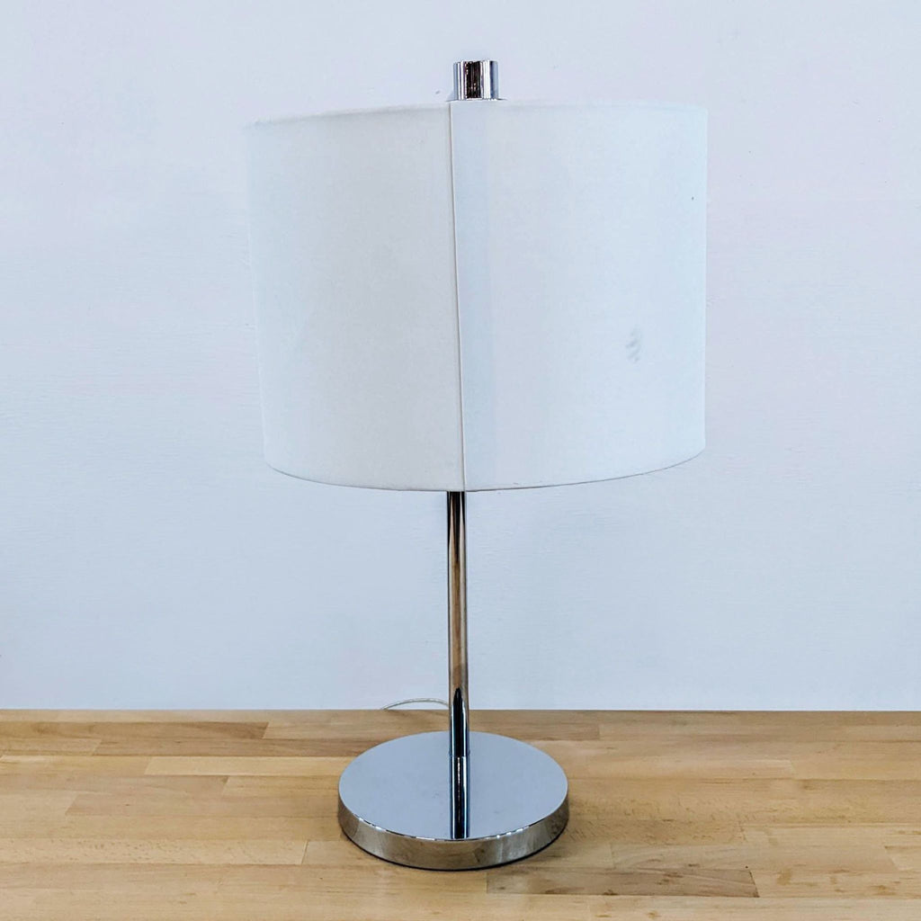 3. Lighting item with metallic chrome base and a clean, cylindrical drum shade.