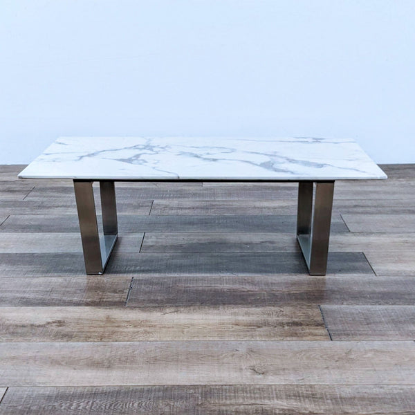 Marble coffee table with metal legs on wooden floor.