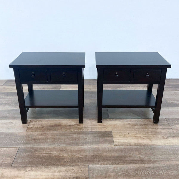 Two dark end tables with drawers and lower shelves, on a wooden floor.