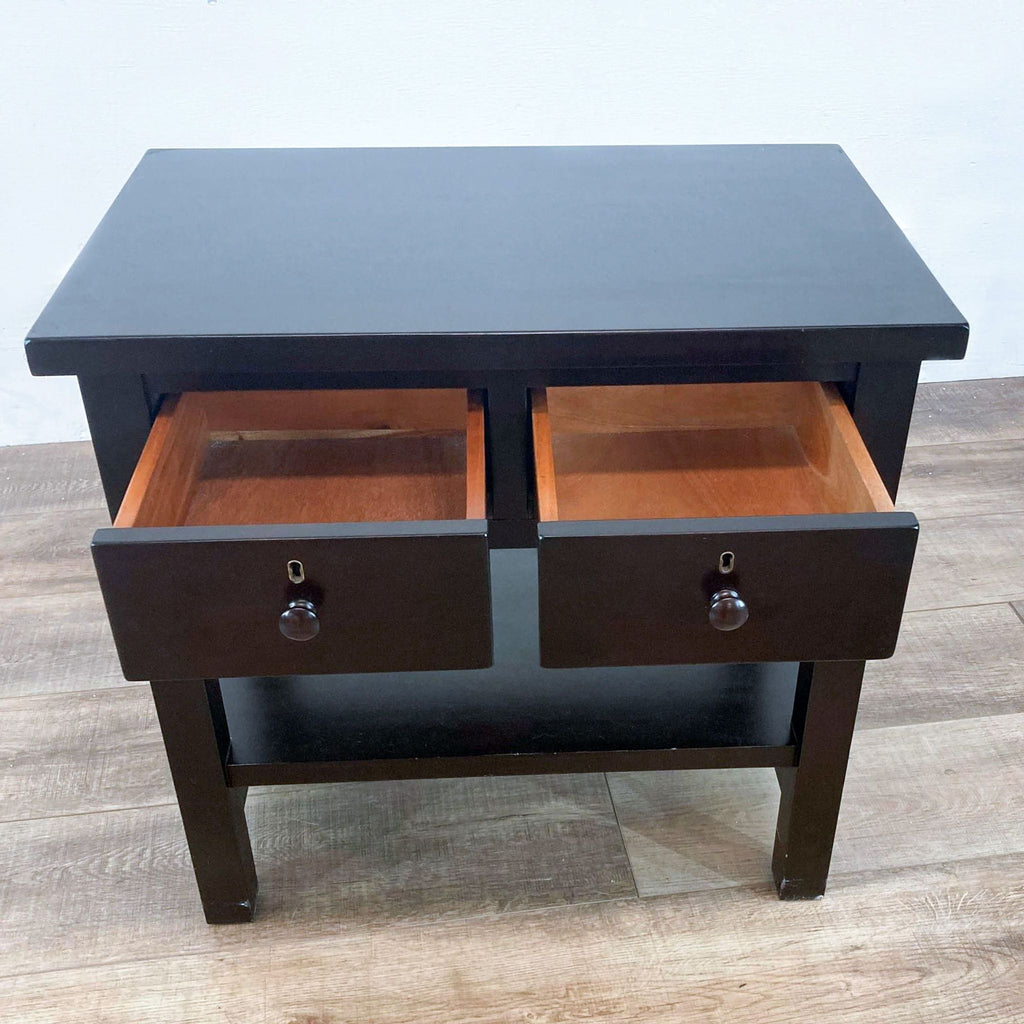 Close-up of an end table with two open drawers on a wooden floor.