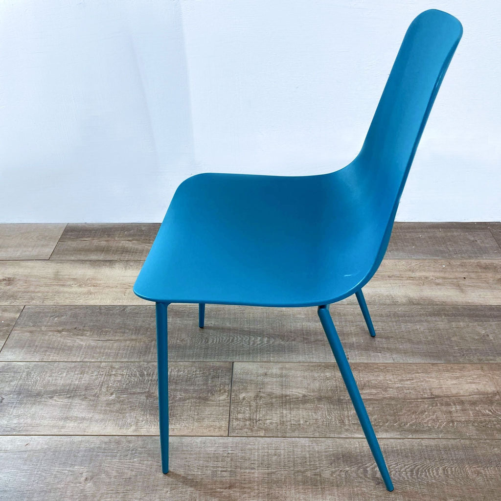 Side view of teal plastic chair with metal legs, showcasing its sleek design.