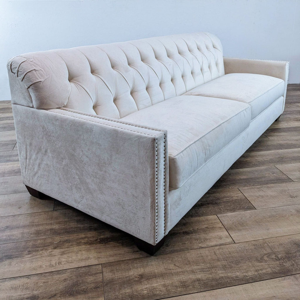 Three-seat sofa in off-white with dark finish feet and tufted design by Reperch.