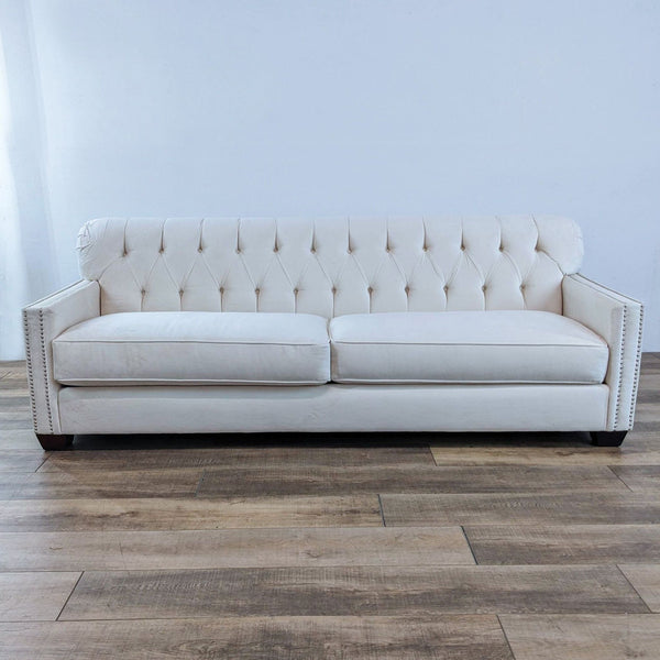 Large off-white sofa with tufted back, narrow track arms, and nail head detailing.