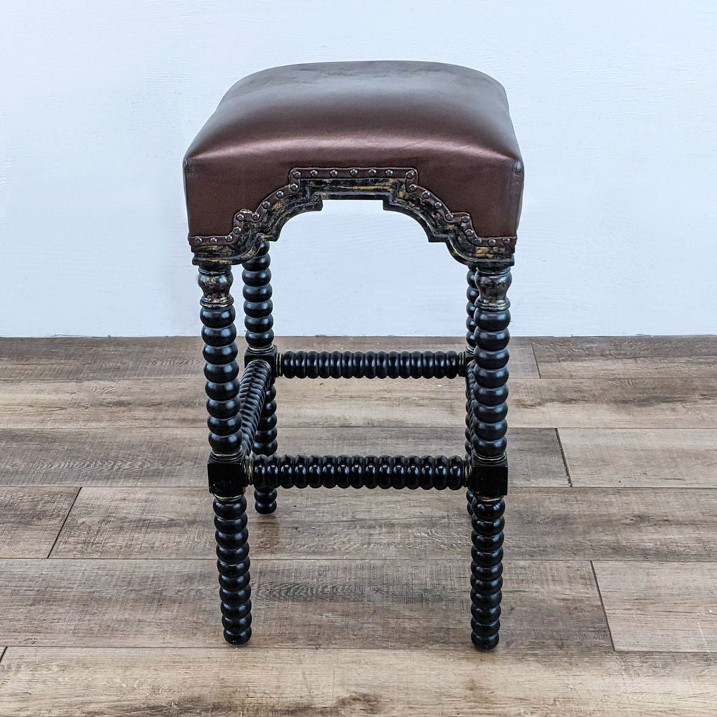 Single bar stool with leather padding, spindle wood legs, and intricate nail head details.