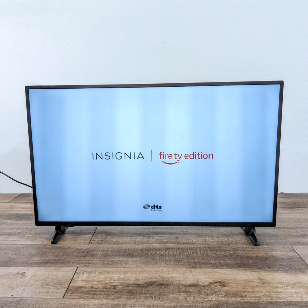 Insignia Fire TV Edition displaying logo on a wooden floor.