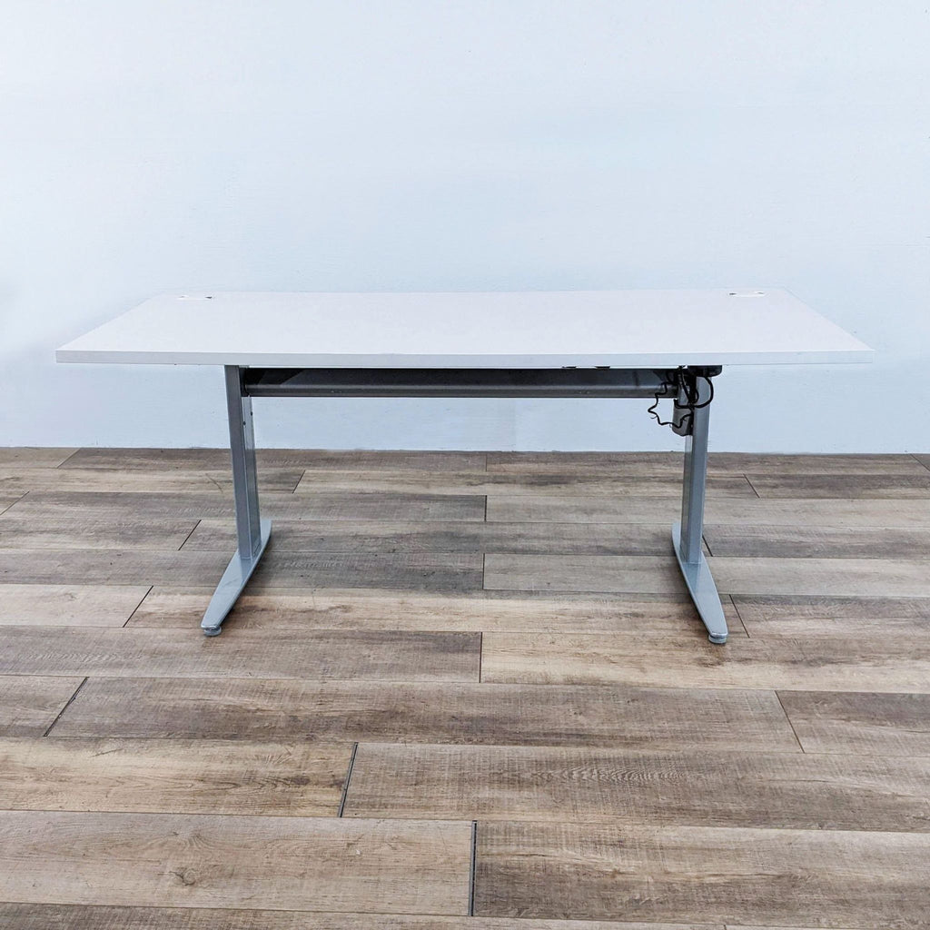 Motorized desk with white top and gray steel frame, adjustable height.  