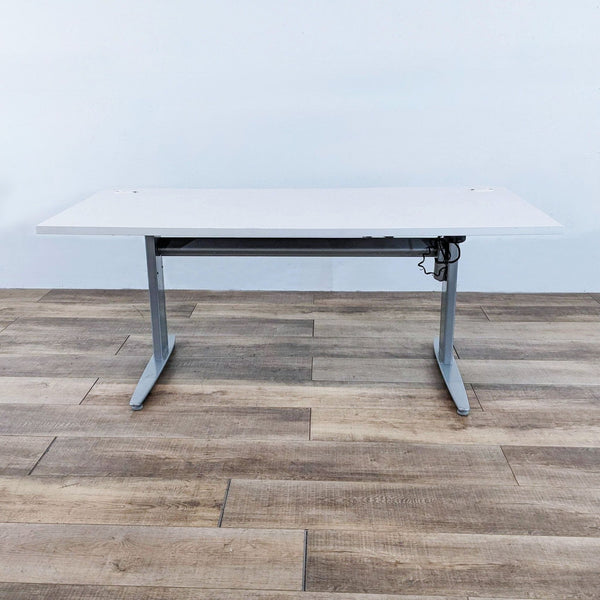 Motorized desk with white top and gray steel frame, adjustable height.  