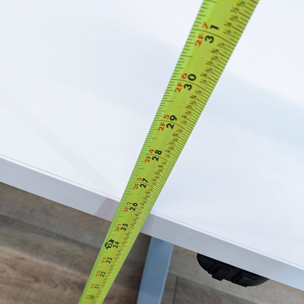 Close-up of tape measure displaying desk height adjustment capability.  