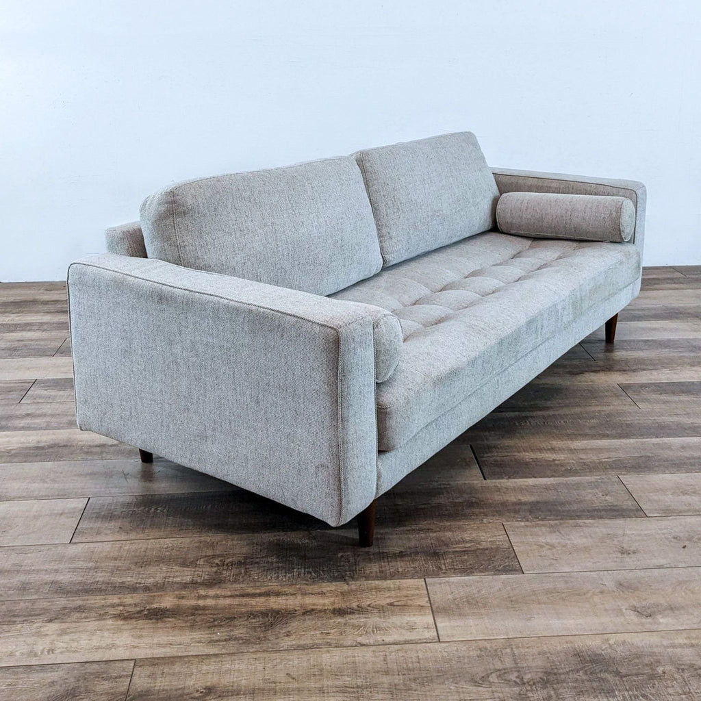 Side view of gray 3-seat sofa with tapered feet and bolster pillows.  
