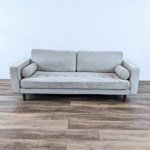 Gray tufted bench seat sofa with track arms and bolster pillows.  