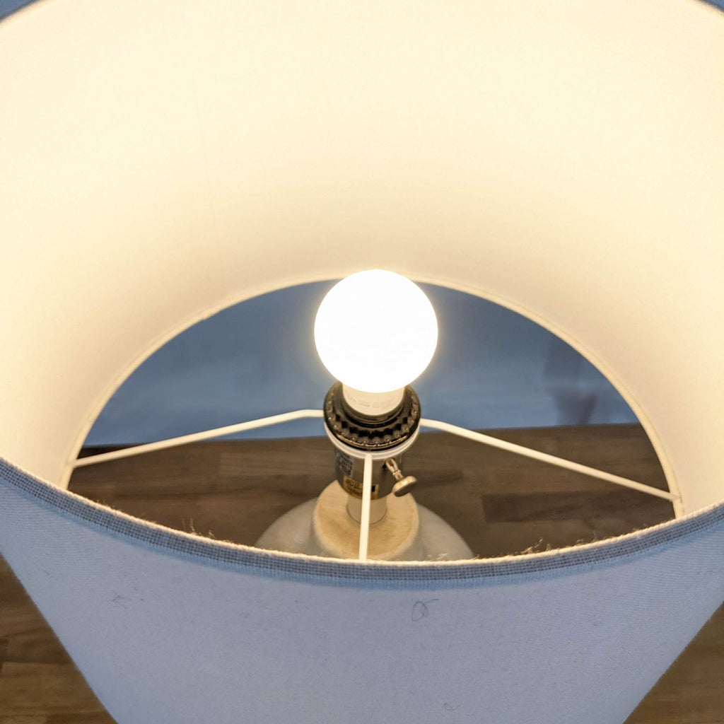Top view of the lit bulb inside the lamp's drum shade.