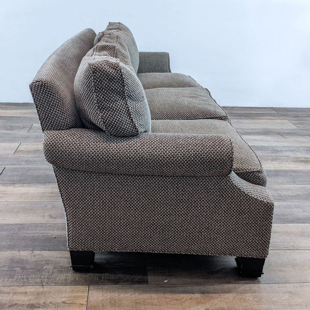 Side view of a 3-seat sofa with rolled arms and wooden feet.
