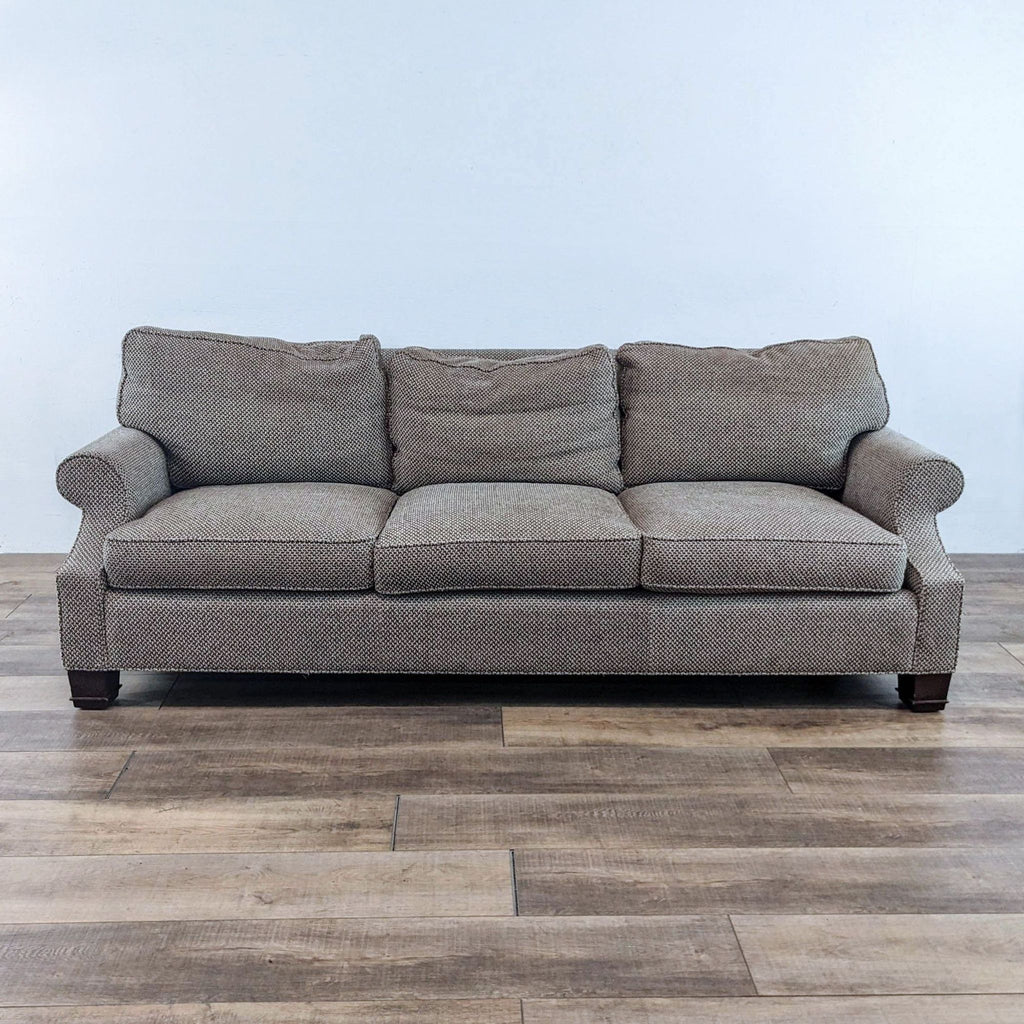 Fabric sofa with rolled arms, wood feet, and small pattern design.