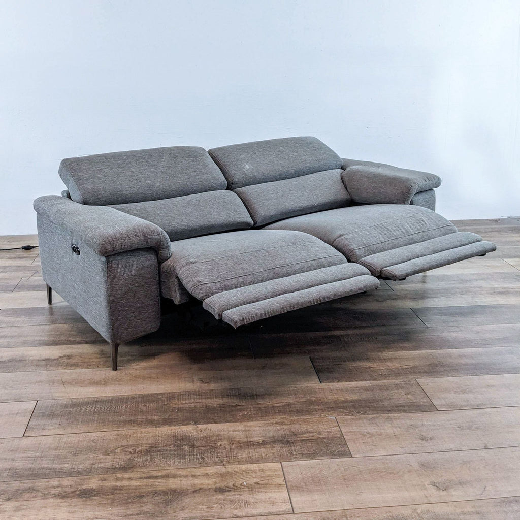 2. Grey dual reclining sofa by Living Space shown with extended footrests and adjustable headrests.