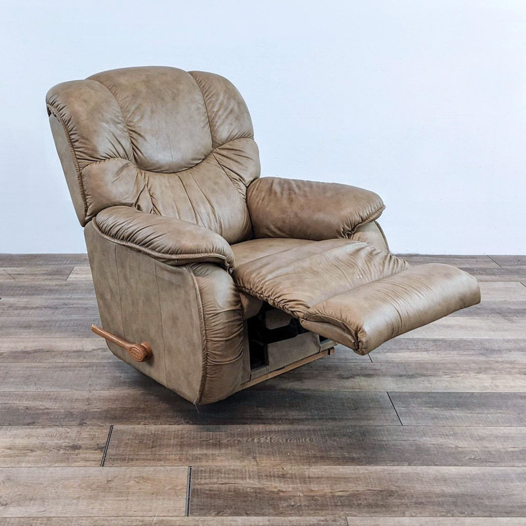 Beige leather recliner with extended footrest, wood handle, on a wooden floor.
