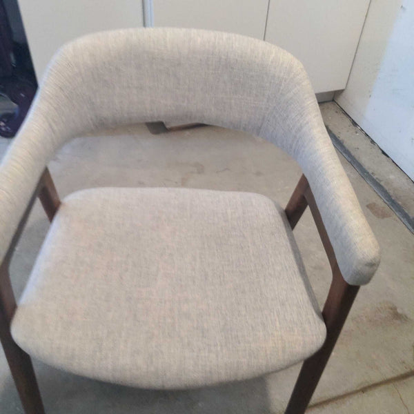 Light gray Reperch dining chair with cushioned seat and curved backrest, shown on a concrete floor.
