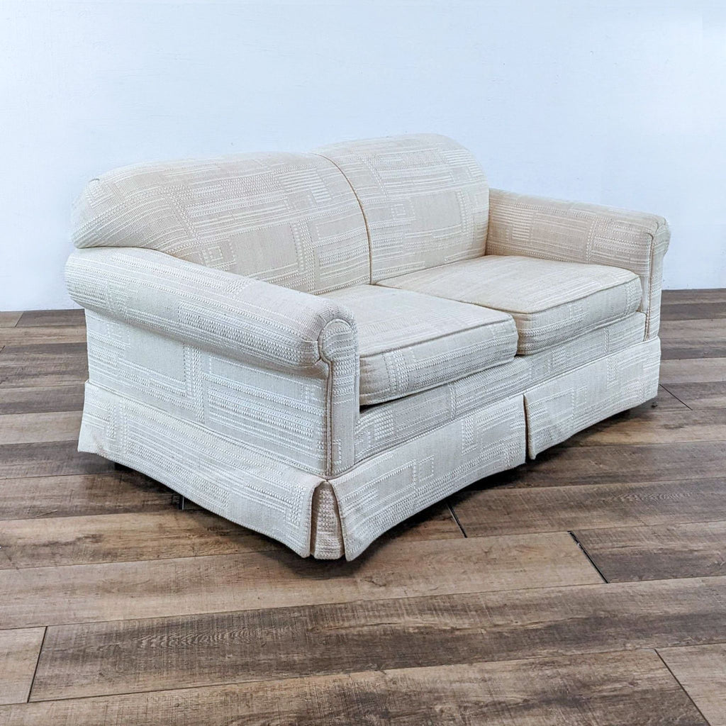 Side angle showing the Reperch off-white fabric loveseat's rounded arms, textured upholstery, and skirted bottom.  