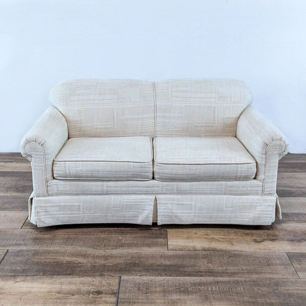 Front view of a Reperch off-white loveseat with rounded arms and a skirted base on wooden flooring.  