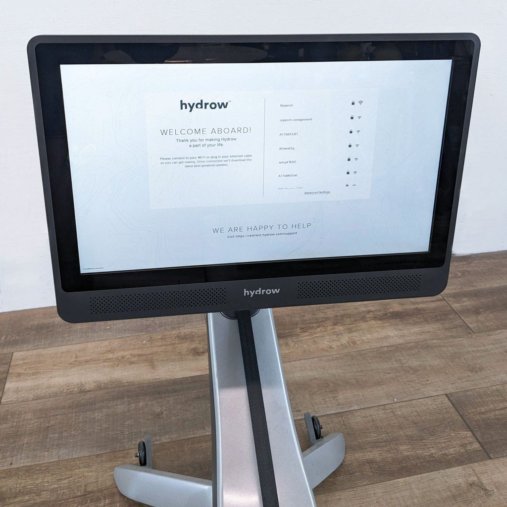 Close-up of the Hydrow rowing machine's welcome screen on a wooden floor.