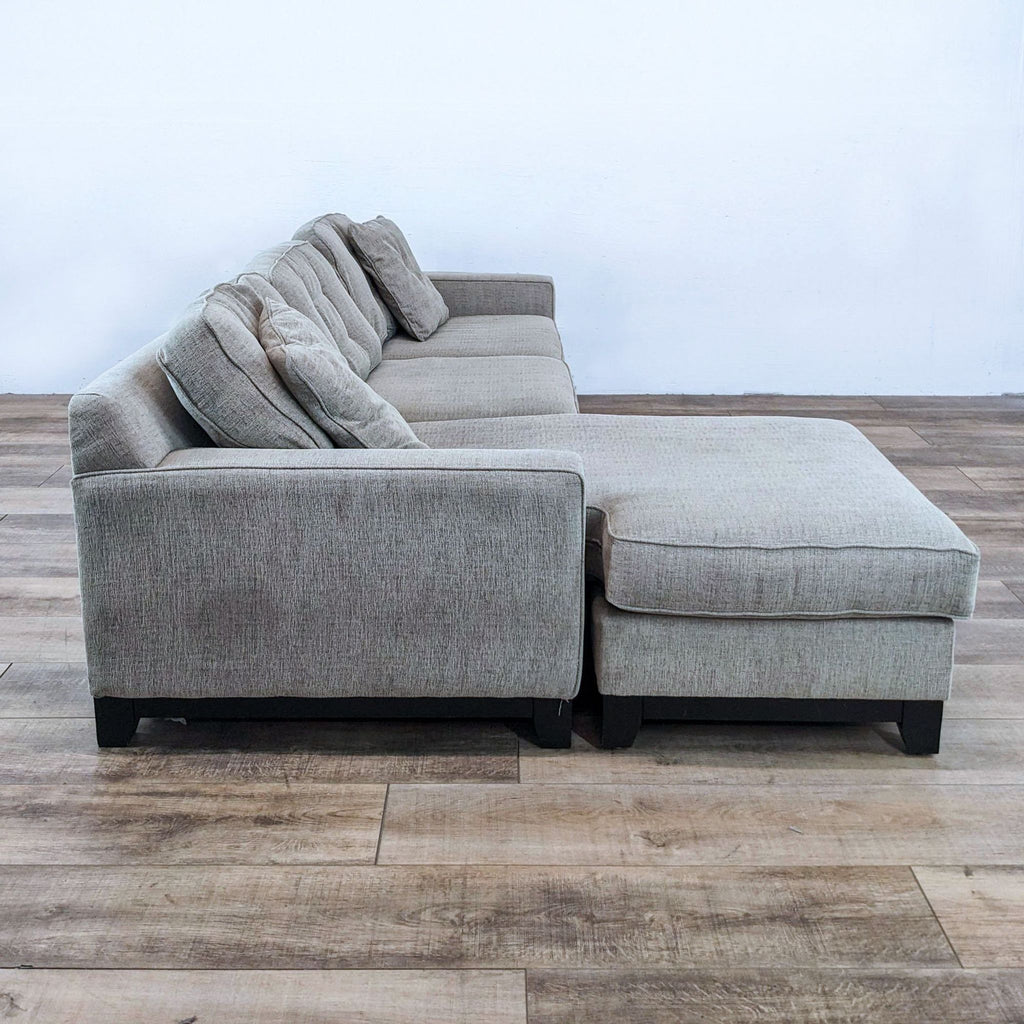 Reversible chaise sectional with fabric cover and dark finish wood legs, by Jonathan Louis.