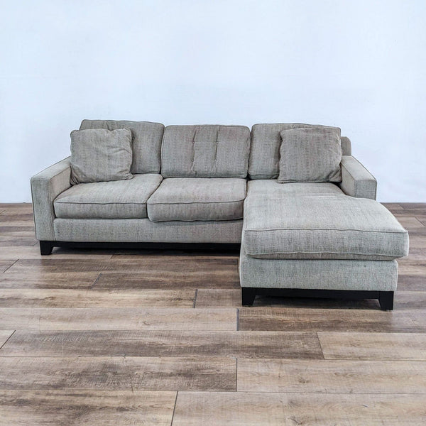 Compact fabric sectional with reversible chaise and dark wooden feet by Jonathan Louis.