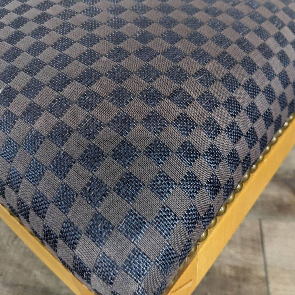 Close-up of checkered upholstery with nailhead detail.