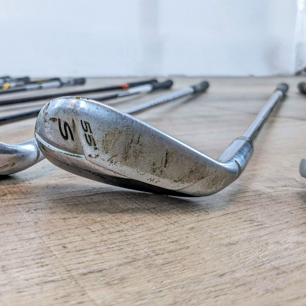 Reperch sand wedge golf club with noticeable wear on hardwood floor.