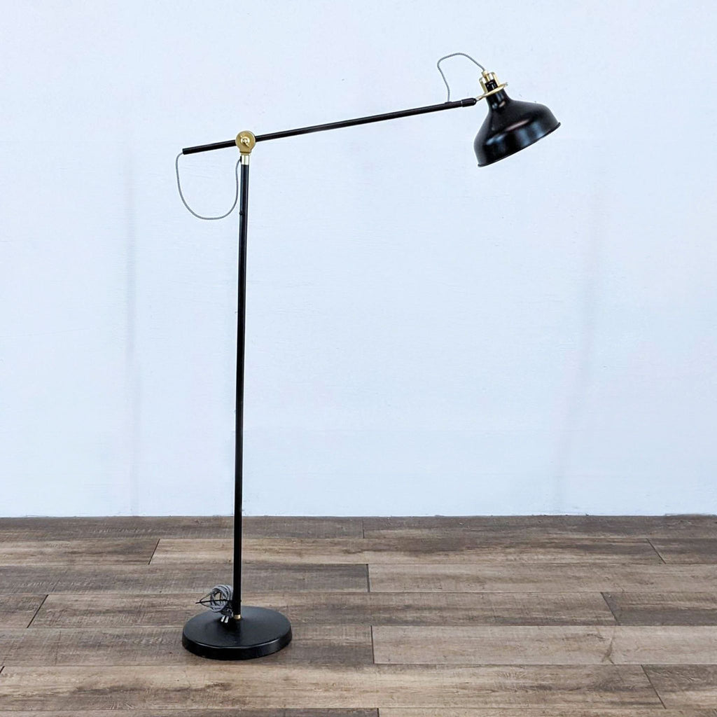RANARP adjustable black floor lamp with a steel joint and round base.