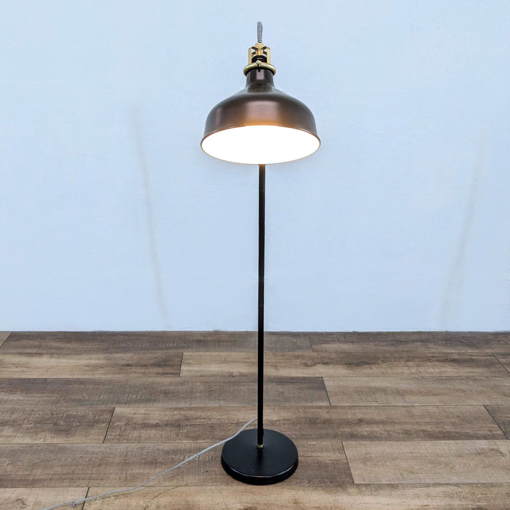 Black floor lamp with a wide shade and simple, minimalist design.