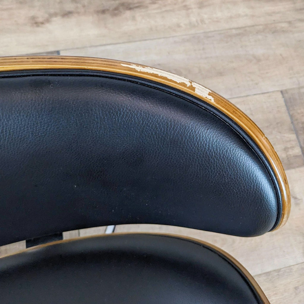 Close-up of chair's faux leather seat and scuffed wood edge detail.