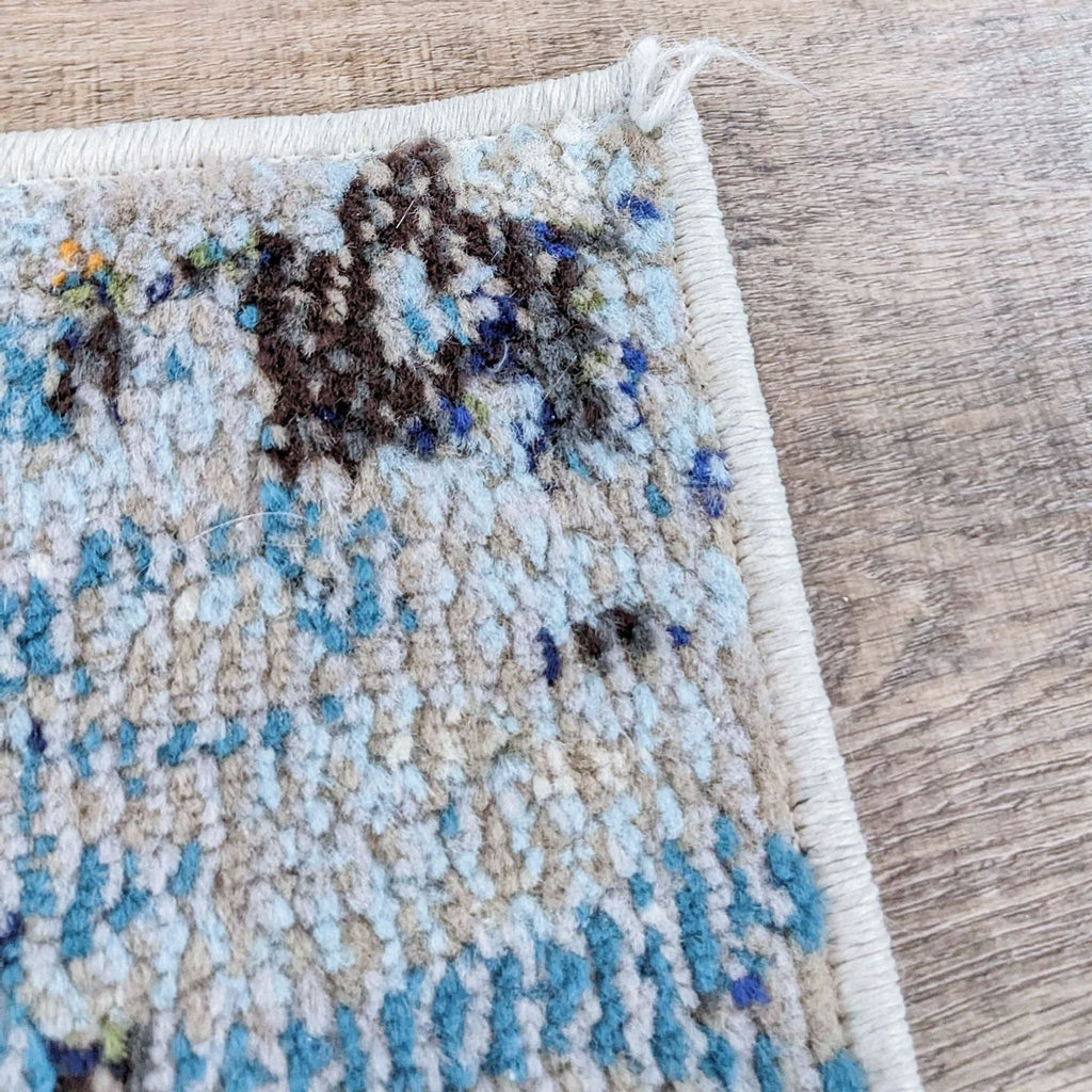 Close-up of textured edge of Madison Blue Gray rug on wooden floor.