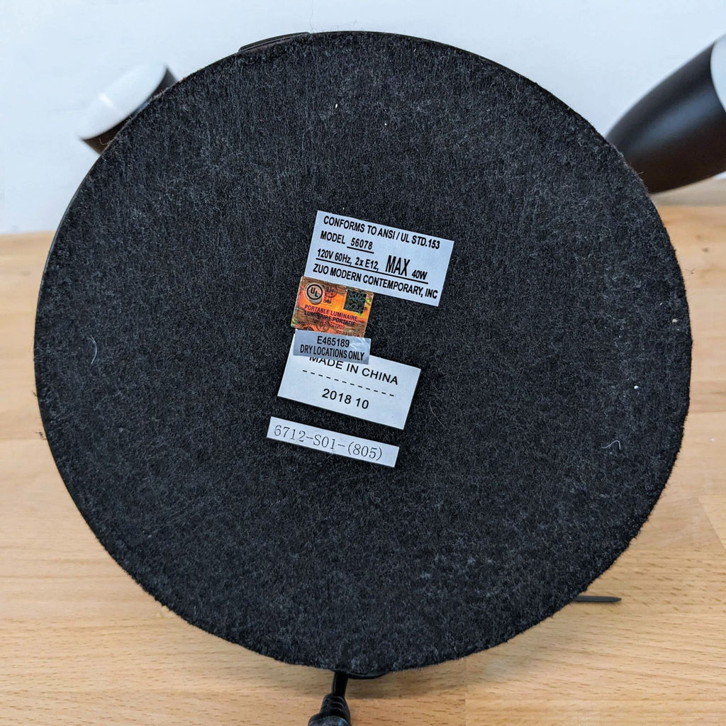 3. Underside of a Zuo Modern lamp base displaying product labels, model details, and manufacturing information.