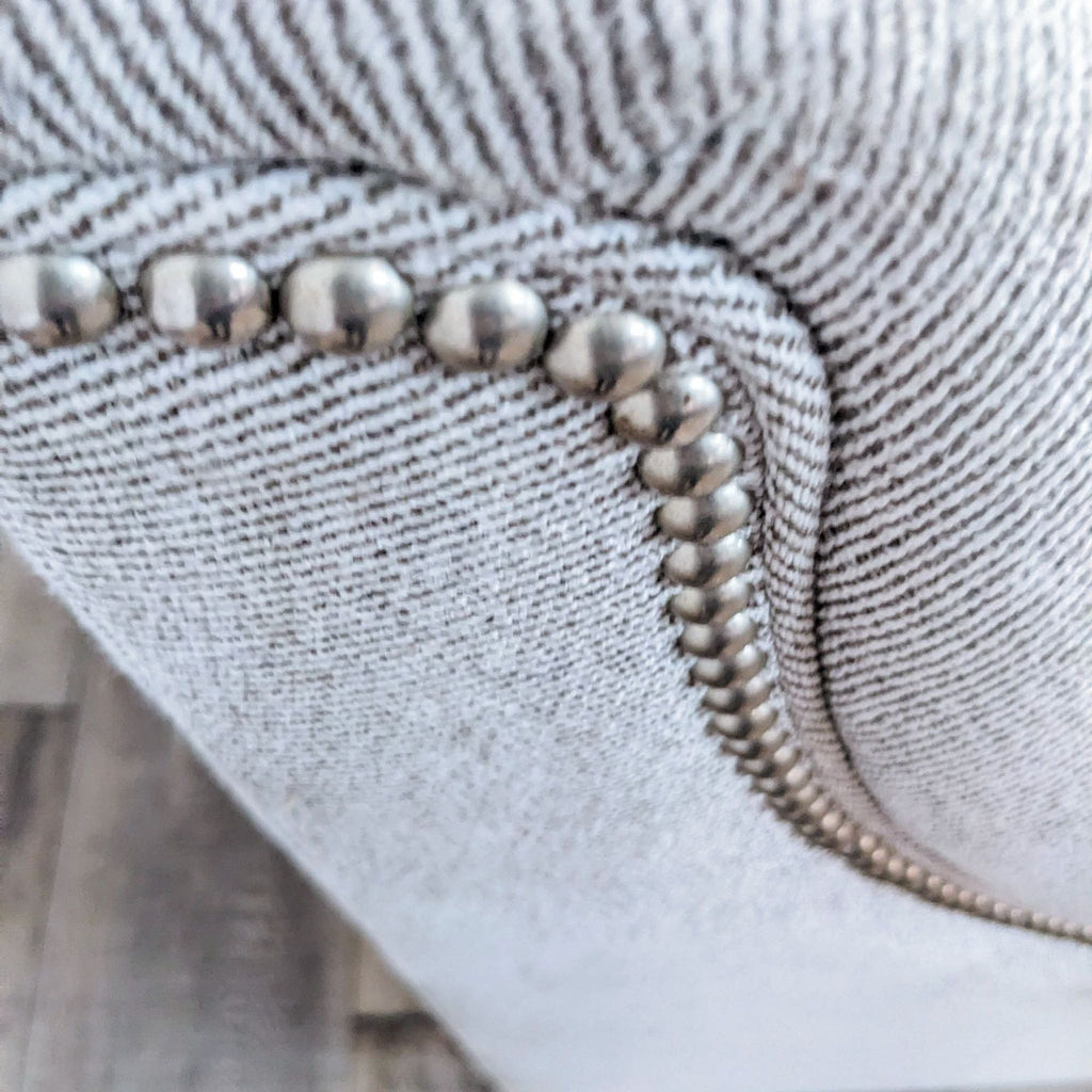 Close-up of the sofa's metallic nail head detailing on textured fabric.