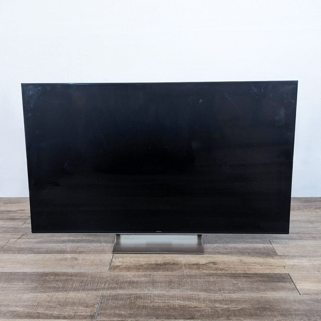 Sony TV on a wooden floor with the screen off.
