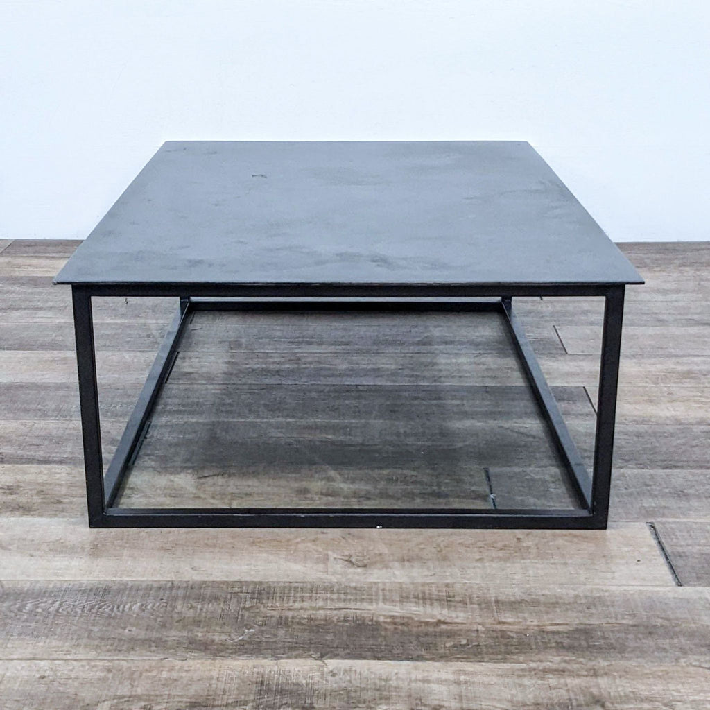 Minimalist metal coffee table on wooden floor, square-pipe base.