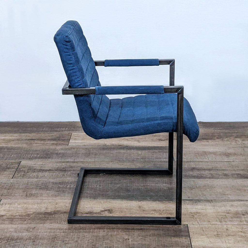 Side view of a dining chair with blue upholstery and sleek metal frame. Contemporary design.